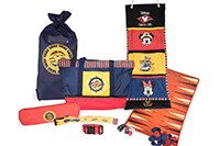 Family Nautical Package A tote bag, a checkered game board, 2 luggage straps sit on a stateroom bed while a gift hanger with storage pouches hangs on a hook on the wall