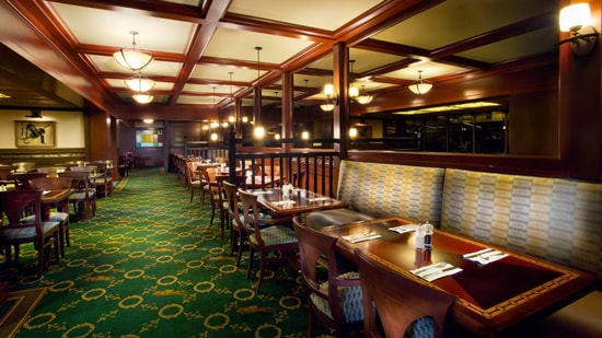 A cocktail lounge with tables, chairs, wood-beamed ceilings and patterned rugs