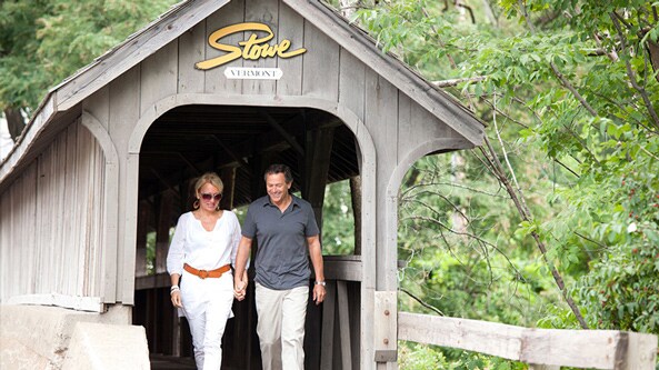 A couple walking along a wooden bridge in Stowe Vermont
