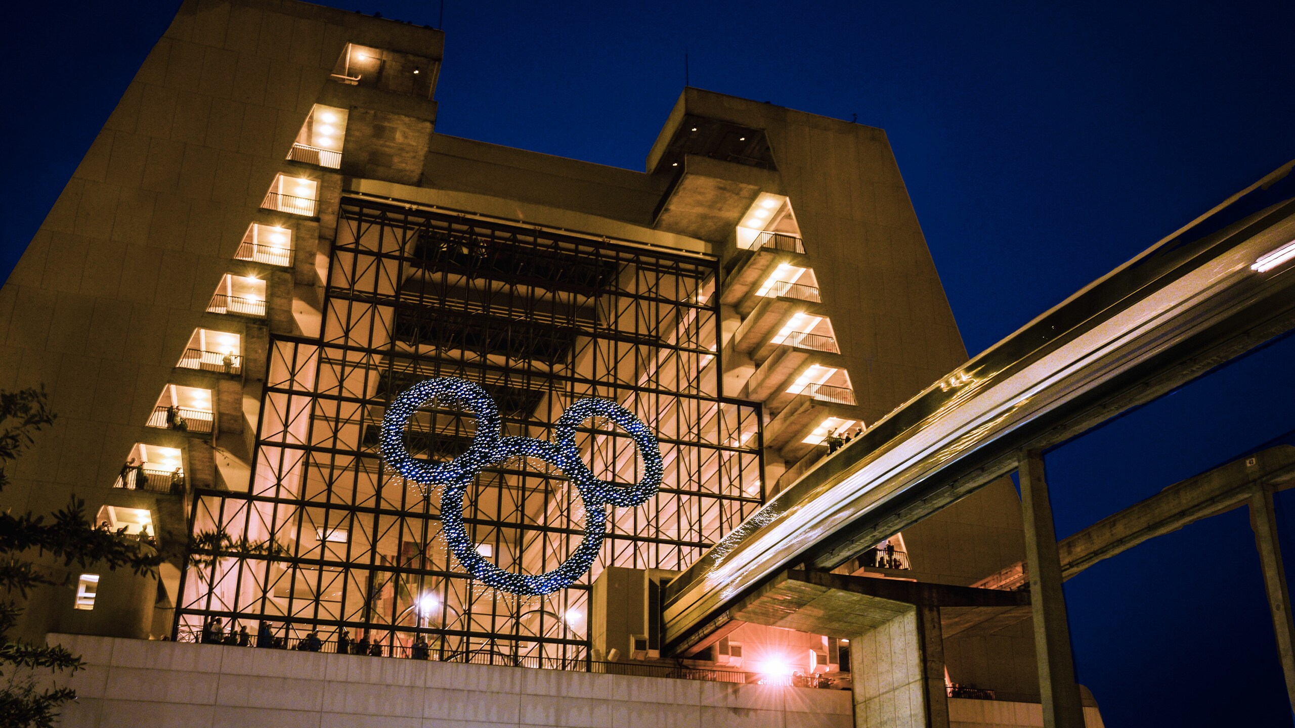 A shimmery Mickey ears wreath hangs from the an overhang near an entrance to Disney's Contemporary Resort